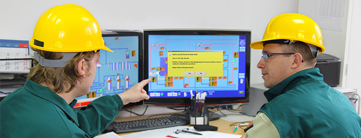 Two men looking at a dual screen computer monitor showing SPC quality process diagrams