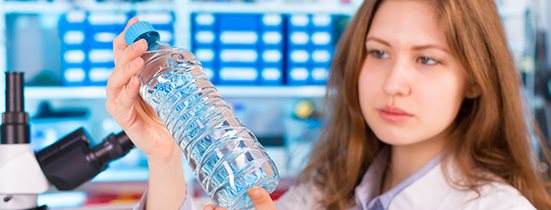 Woman examining a bottle for food and beverage quality control